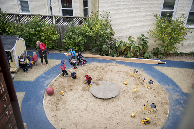 Students at the Child Development Center play outside in the sandbox in the center's exterior playground.