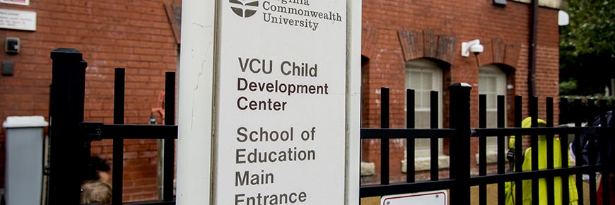 A sign on the front fence of the Child Development Center that says 'VCU Child Development Center, School of Education Main Entrance'.