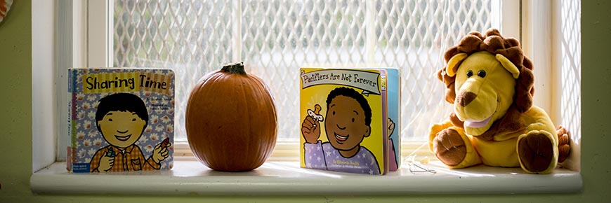 Children's books and a stuffed lion sit on a window sill in Classroom G-1 of the Child Development Center.